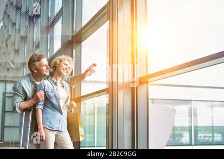 Mature Man Hugging His Wife From Behind While Looking Through The