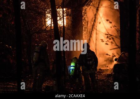 Fully Engulfed House Fire Firefighter In Shadow In Front Of Fire Stock