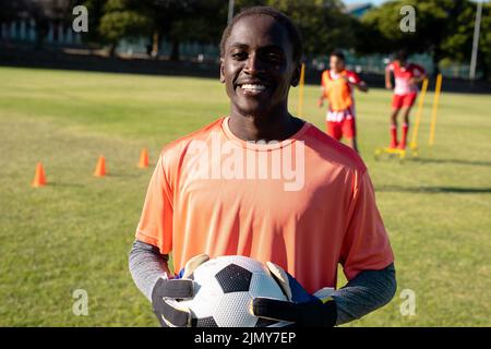 Portrait Of African American Smiling Goalkeeper Wearing Gloves Holding