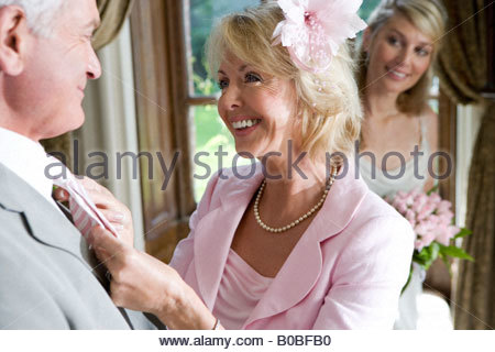 http://l450v.alamy.com/450v/b0bfb0/mature-woman-adjusting-husbands-tie-bride-in-background-smiling-close-b0bfb0.jpg