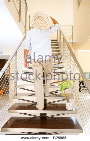 Man walking up stairs in strange old building with iron rail and Stock