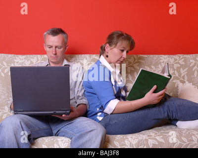 http://l450v.alamy.com/450v/baj3f8/young-couple-sitting-on-sofa-spending-time-together-guy-working-with-baj3f8.jpg