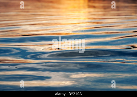 Golden Light Reflecting On Rippling Water Surface Creating Texture