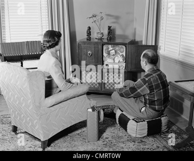 Living Room 1950s 1950s couple husband and wife watching tv in living room smiling Living Room 1950s 1950s couple husband and wife watching tv in living room smiling
