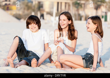 Preteen Girl Sitting On Beach With Barefeet Hugging Knees Stock Photo