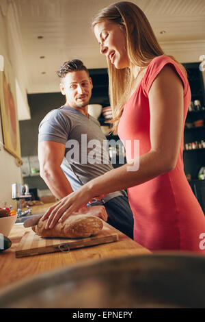 http://l450v.alamy.com/450v/epnepy/shot-of-young-couple-standing-in-kitchen-young-woman-cutting-bread-epnepy.jpg