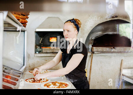 Pizza Restaurant Kitchen young female chef making pizza in restaurant kitchen stock photo Pizza Restaurant Kitchen young female chef making pizza in restaurant kitchen stock photo