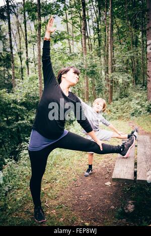 http://l450v.alamy.com/450v/fep8wj/mother-and-son-in-forest-legs-raised-on-picnic-table-stretching-bludenz-fep8wj.jpg