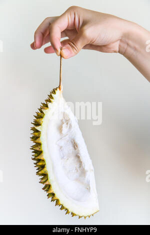 a piece of durian peel held by the stem by the hand of a young woman fnhyp9