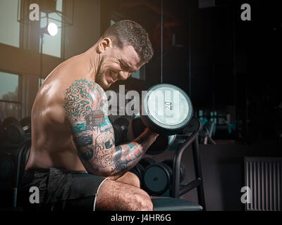 Very Brawny Guy Bodybuilder Execute Exercise With Weight Stock Photo