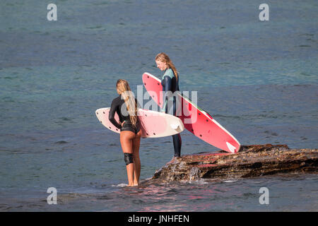 Two young female surfer girls walk out to the surf Zuma ...