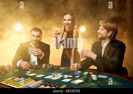 group of young rich people is playing poker in the casino two men