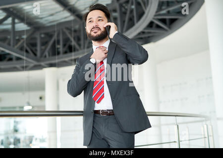 Portrait Of A Businessman Adjusting His Tie And Talking On A Mobile