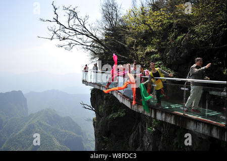 Tourists Walk On The Glass Skywalk On The Cliff Of Tianmen Mountain Or