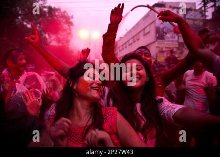 Devotees With Color Smeared Faces Dance On A Road During A Procession