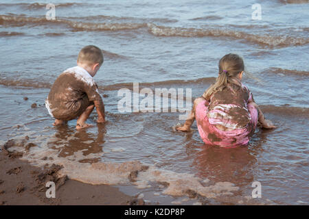 ein kleiner Junge mit schmutzigen Rüsseln steht am Ufer 