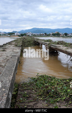 Peligro de ver con puente dañado a través de río en temporada de