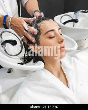 Méconnaissable coiffeur professionnel lavage des cheveux de son client