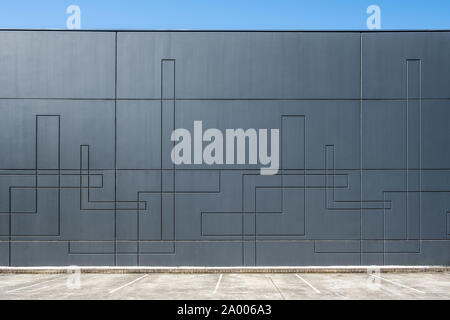 Dark gray concrete wall of industrial building with geometric pattern with empty parking spaces Stock Photo