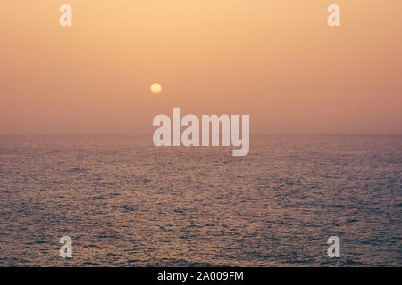 sunset on water, sun going down behind ocean - Stock Photo