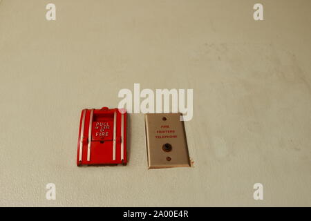 Closeup manual pull station of fire alarm system installed on the wall next to fire fighters telephone jack, selective focus, safety concept, Stock Photo