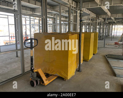 Piled cinder blocks wrapped in yellow packaging on the floor of the prefabricated multi-storey building at the construction site Stock Photo