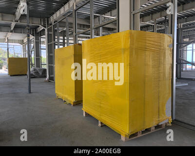 Piled cinder blocks wrapped in yellow packaging on the floor of the prefabricated multi-storey building at the construction site Stock Photo