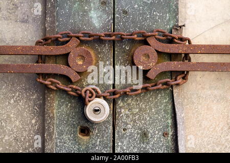 Old metallic padlock with rusty vintage chain hangs on old door, security concept Stock Photo