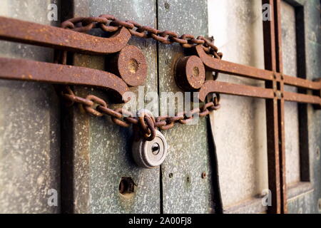 Old metallic padlock with rusty vintage chain hangs on old door, security concept Stock Photo