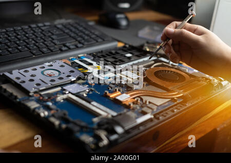 Technician repairing broken laptop notebook computer with screwdriver Stock Photo