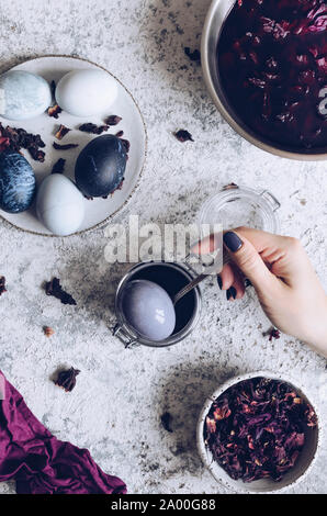 Easter eggs with marble stone effect painted with natural dye carcade flower on grey concrete background. Stock Photo
