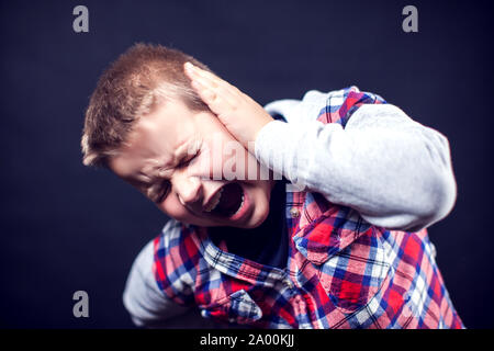 A boy feels strong ear pain. Children, healthcare and medicine concept Stock Photo