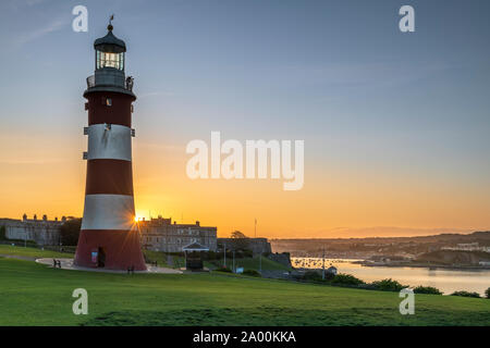 Plymouth, Devon, England. Thursday 19th September 2019. UK Weather. After another clear and chilly night, the first rays of sunshine appear behind Smeatons Tower on The Hoe, lighting up the harbour in Plymouth, Devon, South West England . Terry Mathews/Alamy Live News. Stock Photo