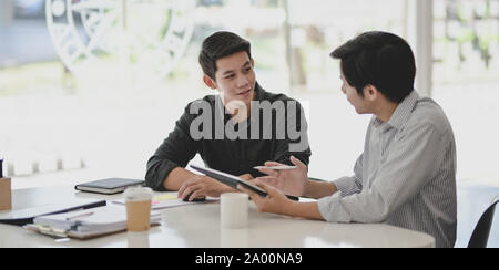 Two professional businessmen discussing their progress of their current project while using tablet Stock Photo