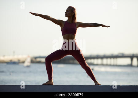 Young sporty woman doing exercise in the city with beautiful view of the sea behind her Stock Photo