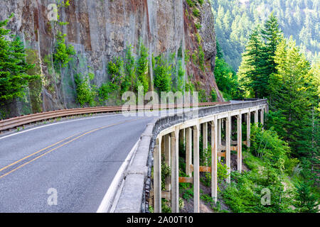 The winding protected road through the bridge on concrete piers around a mountain rock on one side and an abyss on the other side in the scenic area o Stock Photo