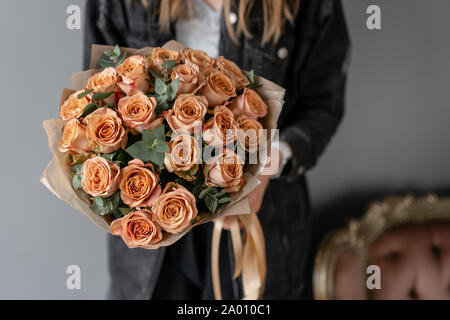 Flowers coffee color, cappuccino roses with eucalyptus. Small Beautiful bouquets in woman hand. Floral shop concept. Flowers delivery Stock Photo