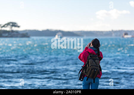 Woman photographer taking pictures of moving boat and harbour. Exploring, adventure concept Stock Photo