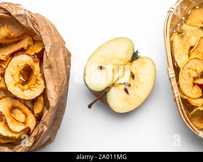 Tasty dried apples chips isolated on white background, in paper bags and fresh half apple, copy space Stock Photo