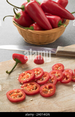 Basket with red Jalapeno peppers and slices close up on a cutting board Stock Photo