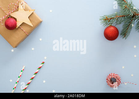 Blue Christmas background with gift box, clew of rope, fir tree branch, red balls, confetti star, drinking straws. Christmas, New Year, winter holiday Stock Photo