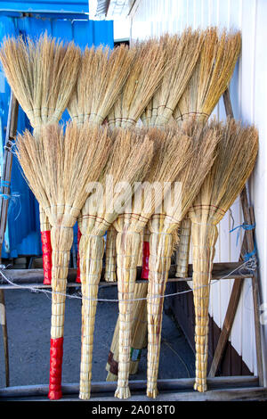 Rows of handmade brooms in a rustic market close-up Stock Photo