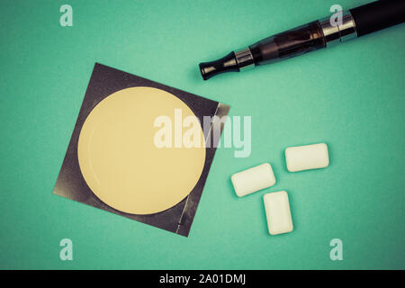 nicotine patch, chewin gum and ecigarette used for smoking cessation isolated on green background Stock Photo