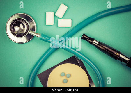 stethoscope and nicotine patch, chewin gum and ecigarette used for smoking cessation isolated on green background Stock Photo