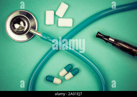 stethoscope, chewin gum, ecigarette ou drug used for smoking cessation isolated on green background Stock Photo