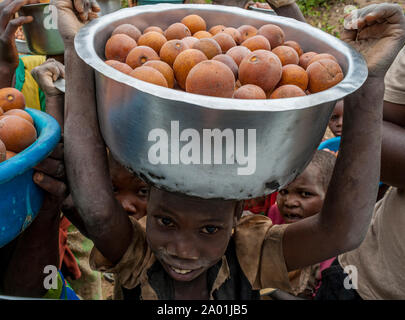 Malawi - young child selling fruit from a bowl on his head looks up at buyer in a passing car Stock Photo