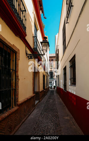 Old picturesque passageway in the medieval Jewish Quarter of Santa Cruz in Seville, Andalusia, Spain.