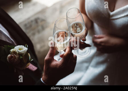 Close up of married couple toasting champagne glasses at wedding party. Hands bride and groom clinking glasses at wedding reception. Stock Photo