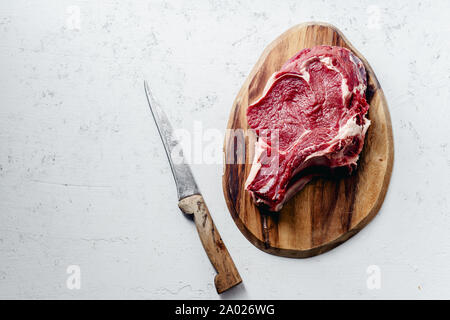 Raw beef steak with a knife on concrete background. Top view Stock Photo