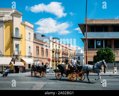 Seville, Spain - Sept 10, 2019: Old horse drawn carriage carrying tourist passengers with vibrant Spanish architecture in background Stock Photo